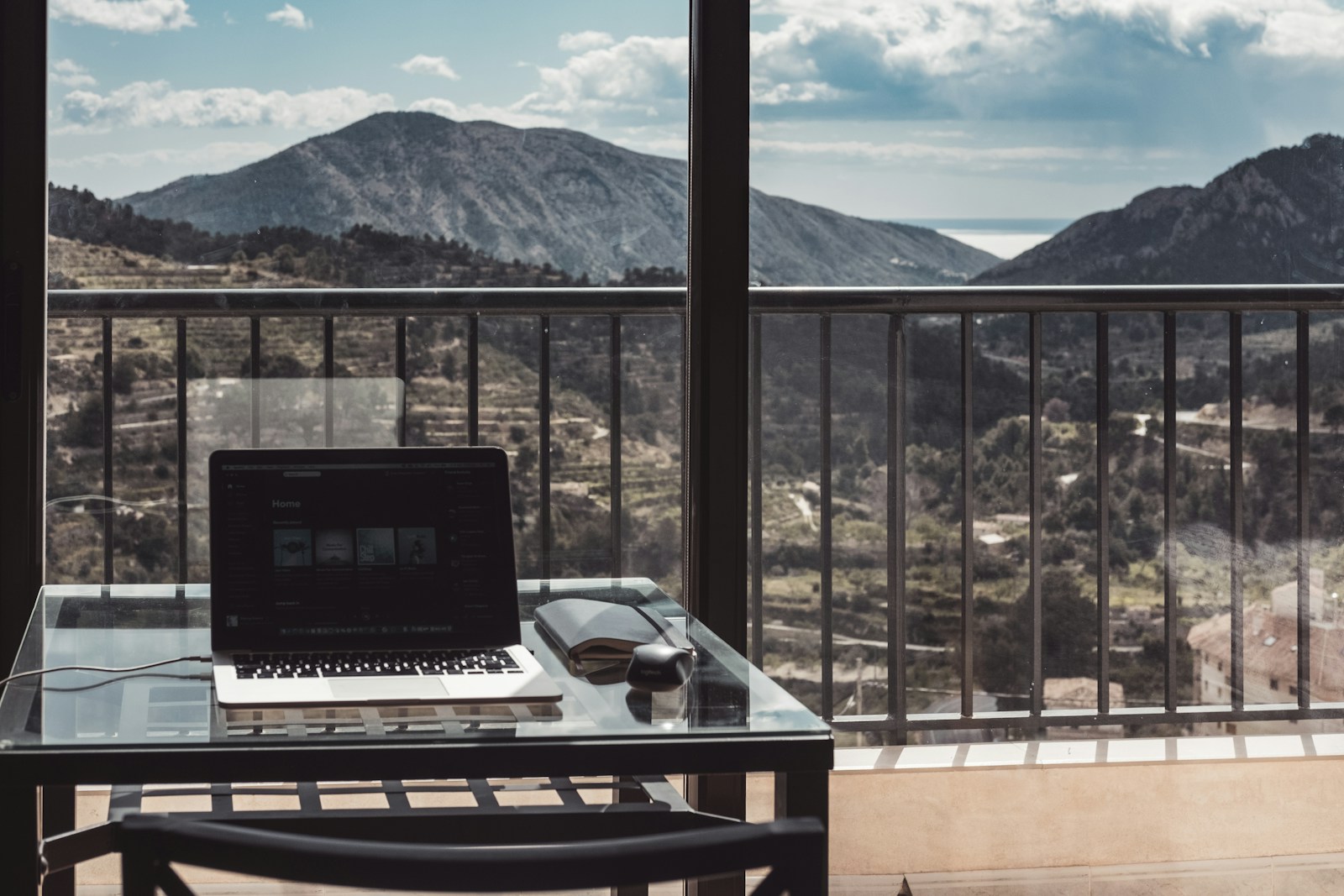 Working remotely from a MacBook on a table overlooking a mountain view.